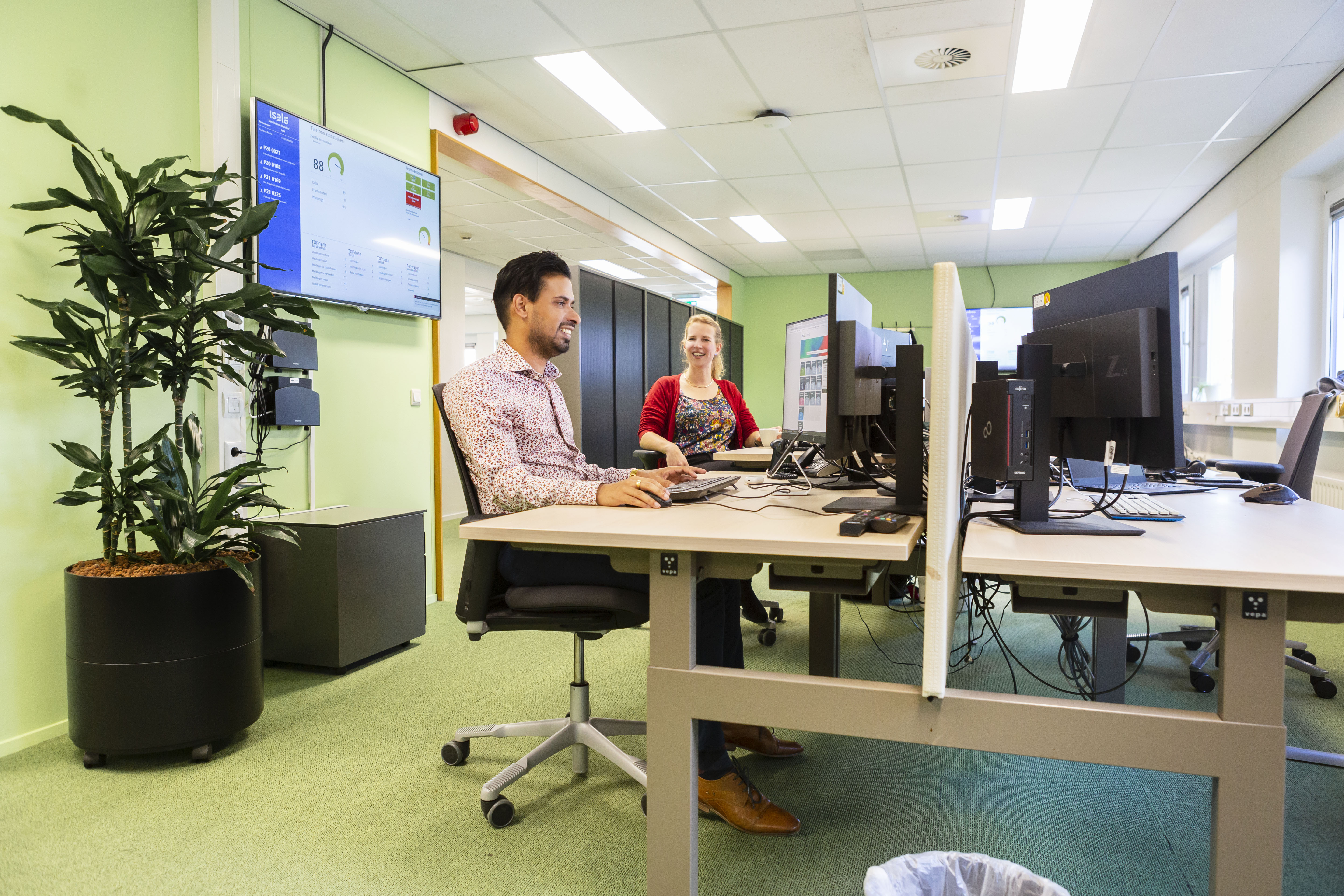 Man en vrouw zitten achter hun bureau met computers