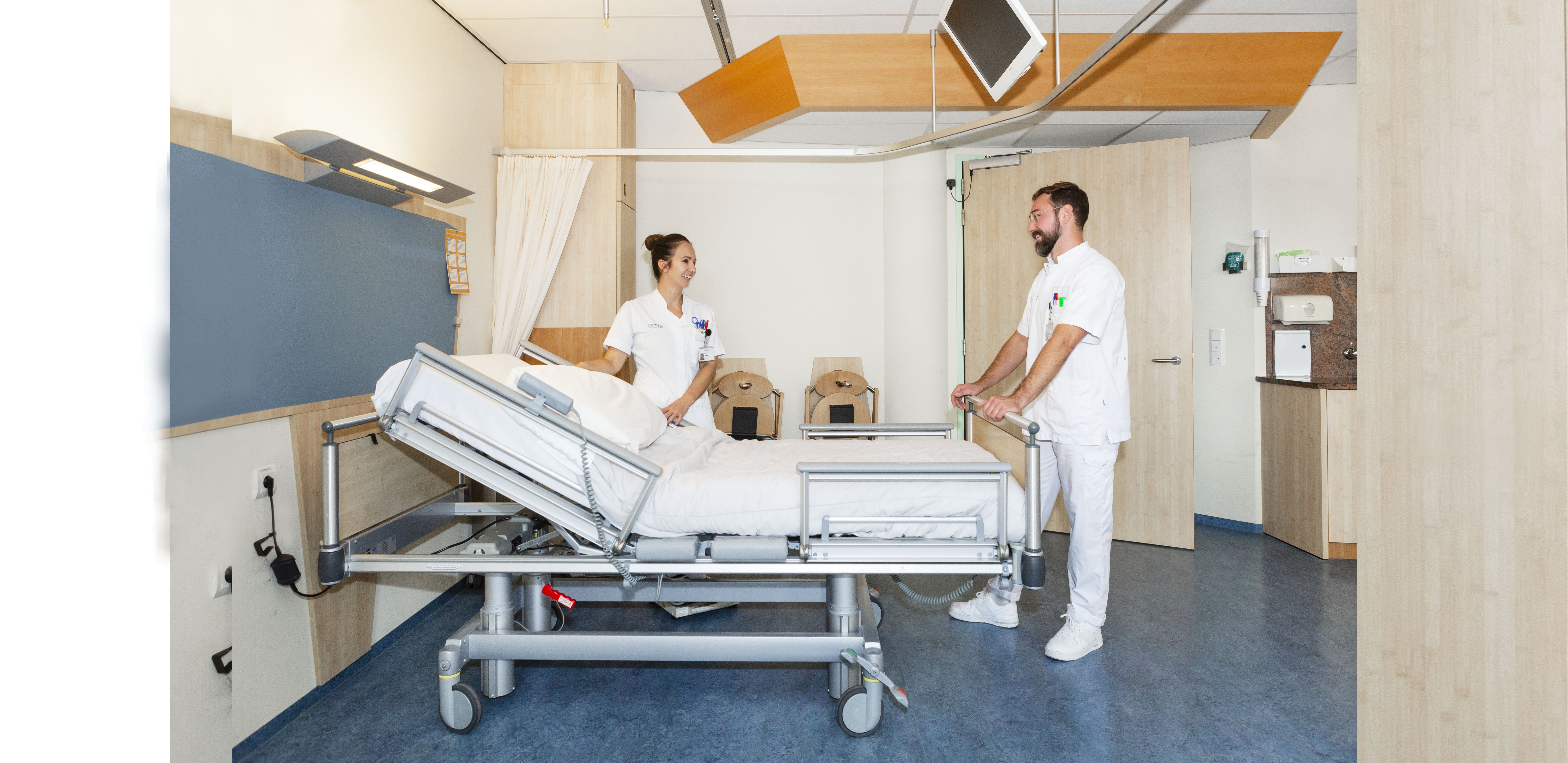 Twee verpleegkundigen in een verpleegkamer bij een bed