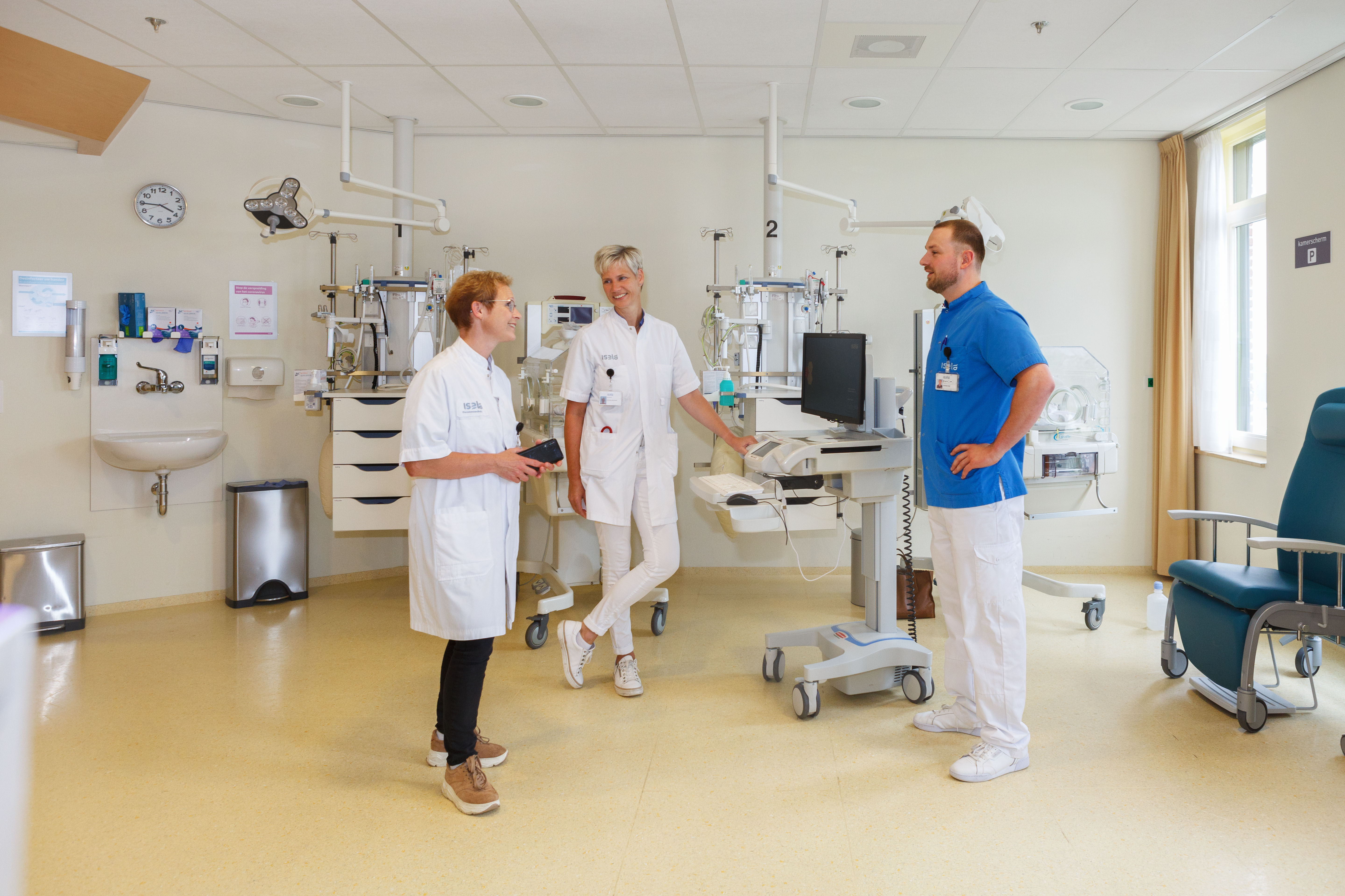 Drie verpleegkundigen in gesprek op een verpleegafdeling
