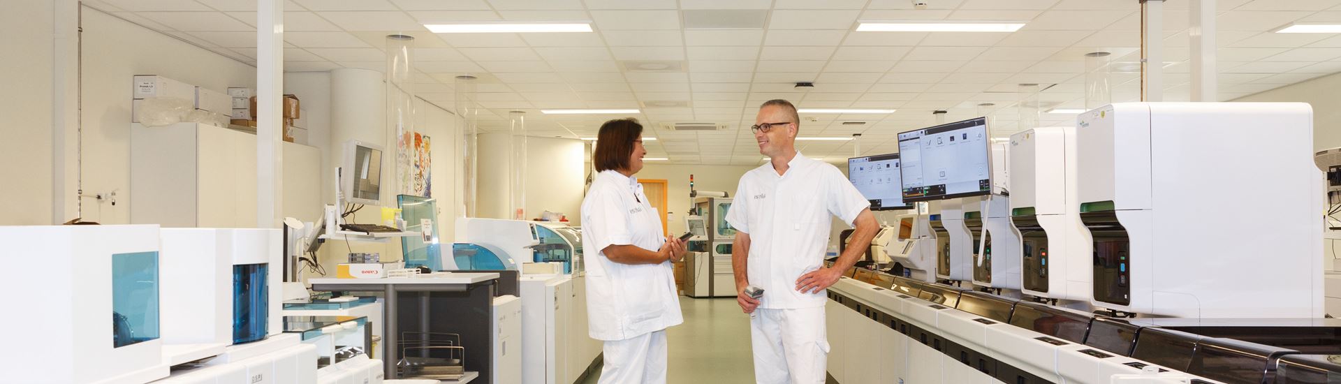 Twee medewerkers van het laboratorium in gesprek bij teststraat Twee medewerkers van het laboratorium in gesprek bij teststraat