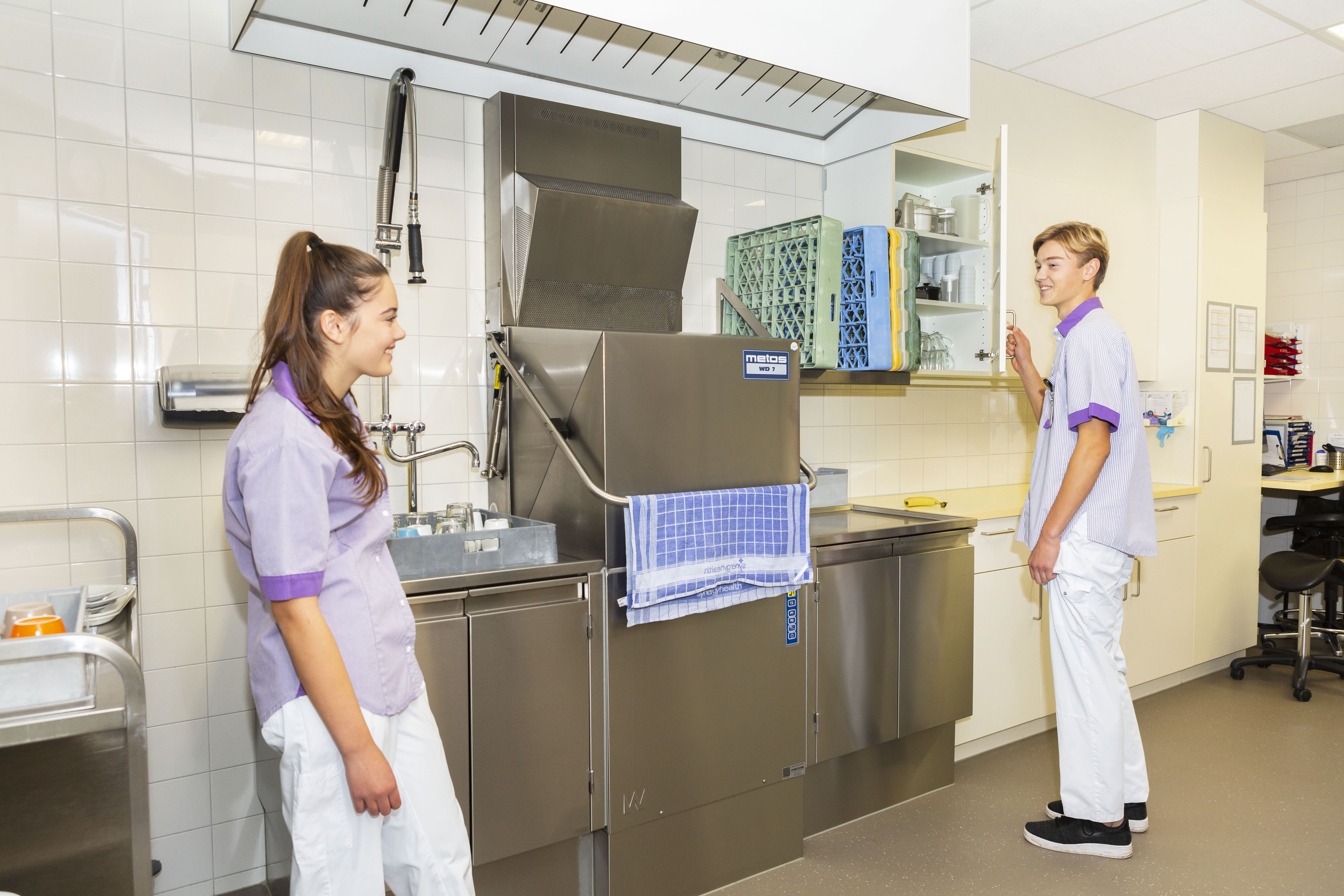 Service assistent en schoonmaker staan in de keuken van een verpleegafdeling